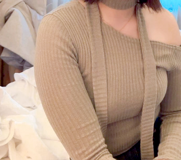 Before photo showing visible bulk on upper arms while seated in ribbed beige top.